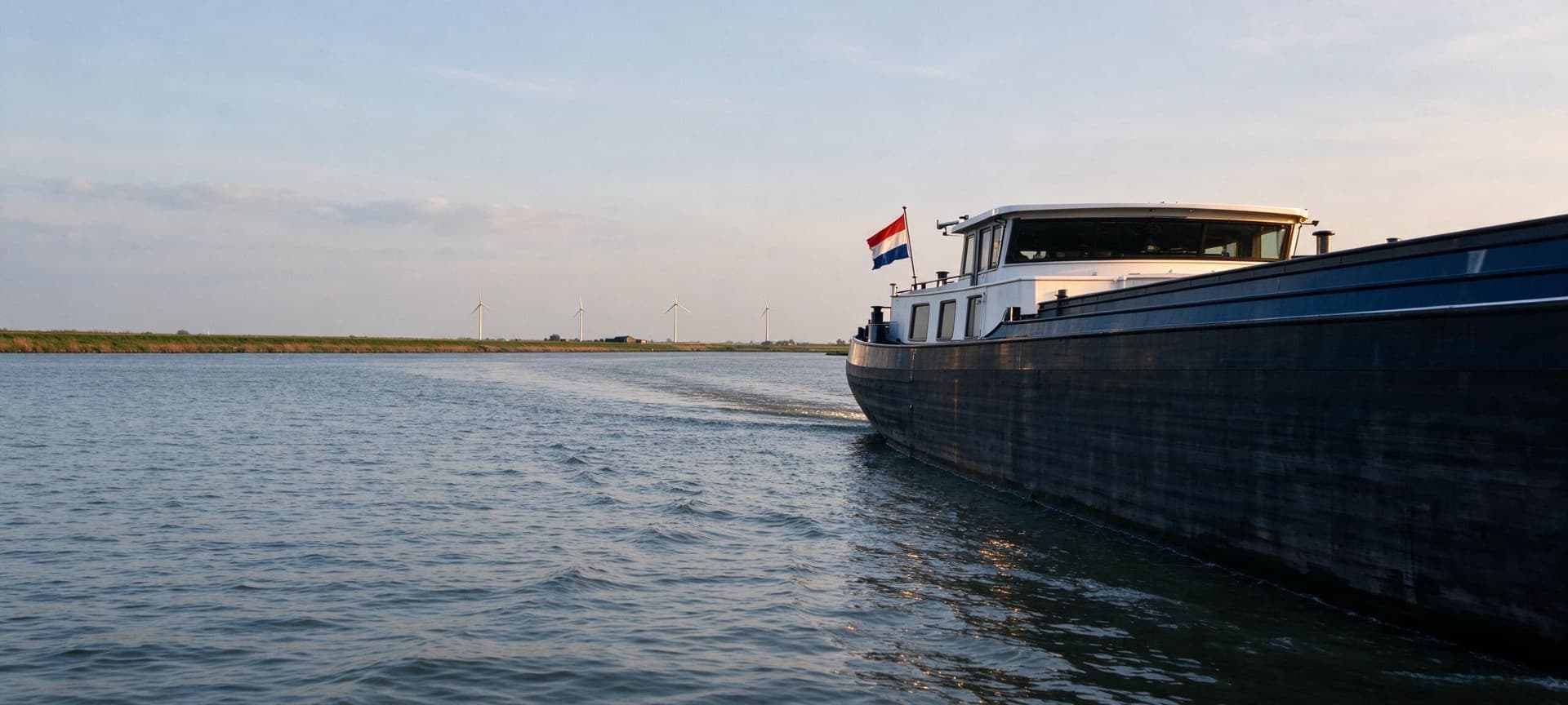 Wheelhouse of an inland ship with a Dutch flag in the polder