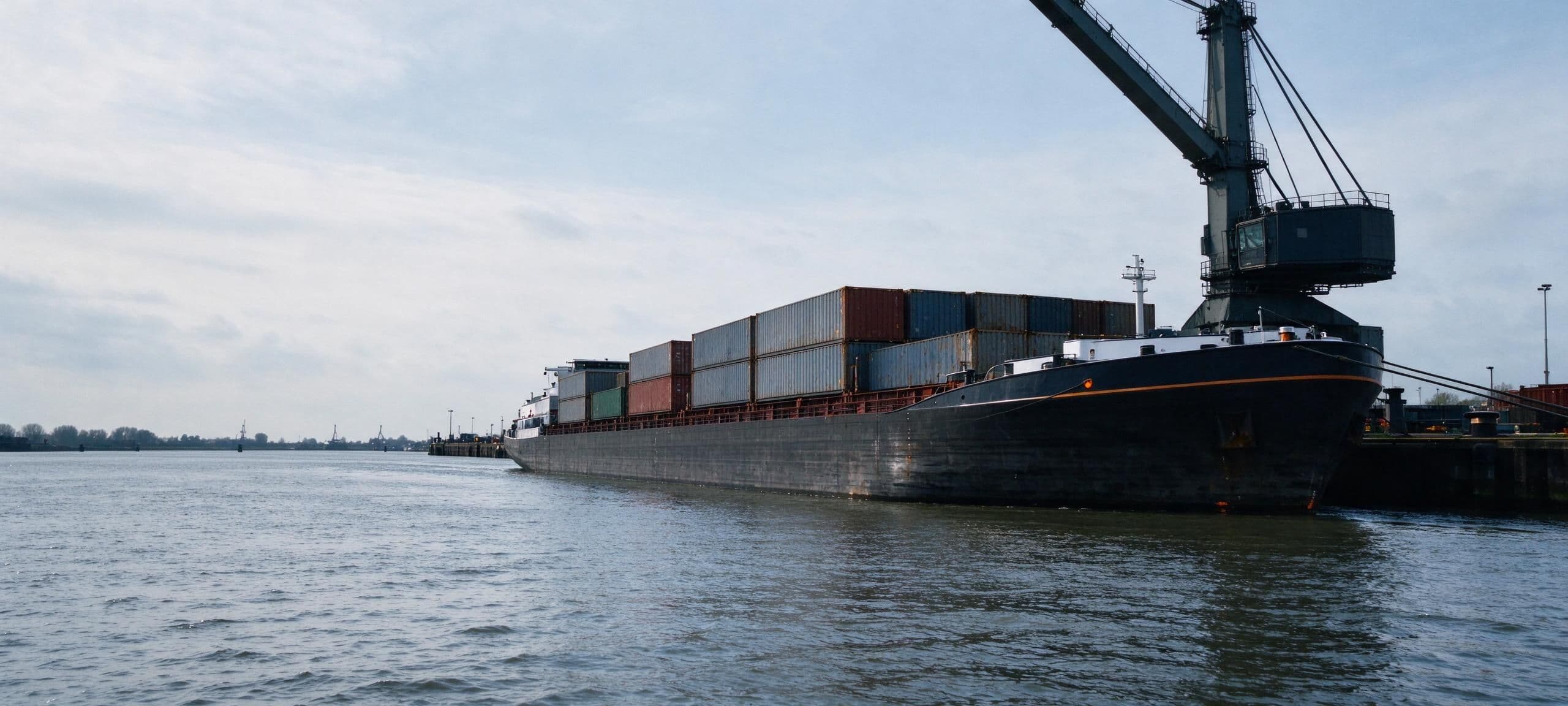 Containerschip afgemeerd aan de kade van een binnenhaven